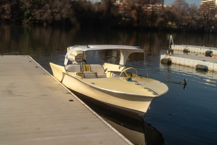 Yellow boat docked on a calm lake with trees in the background.