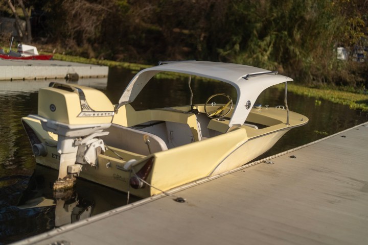 Small yellow motorboat with a canopy docked on a calm lake.