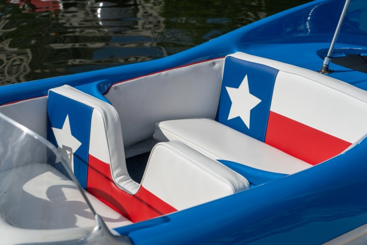 a blue and white boat sitting next to a pool of water