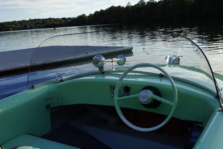 a plane sitting on top of a green boat on a body of water